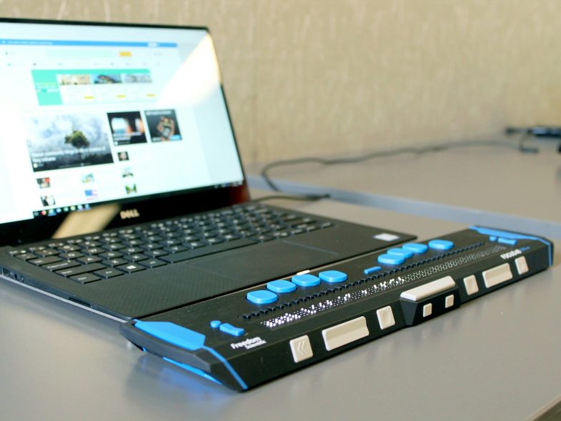 Een braille-leesregel en een laptop waarop een website geopend is.